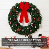 Plug-in pre-lit artificial fir Christmas wreath glowing with LED lights hung on a front door