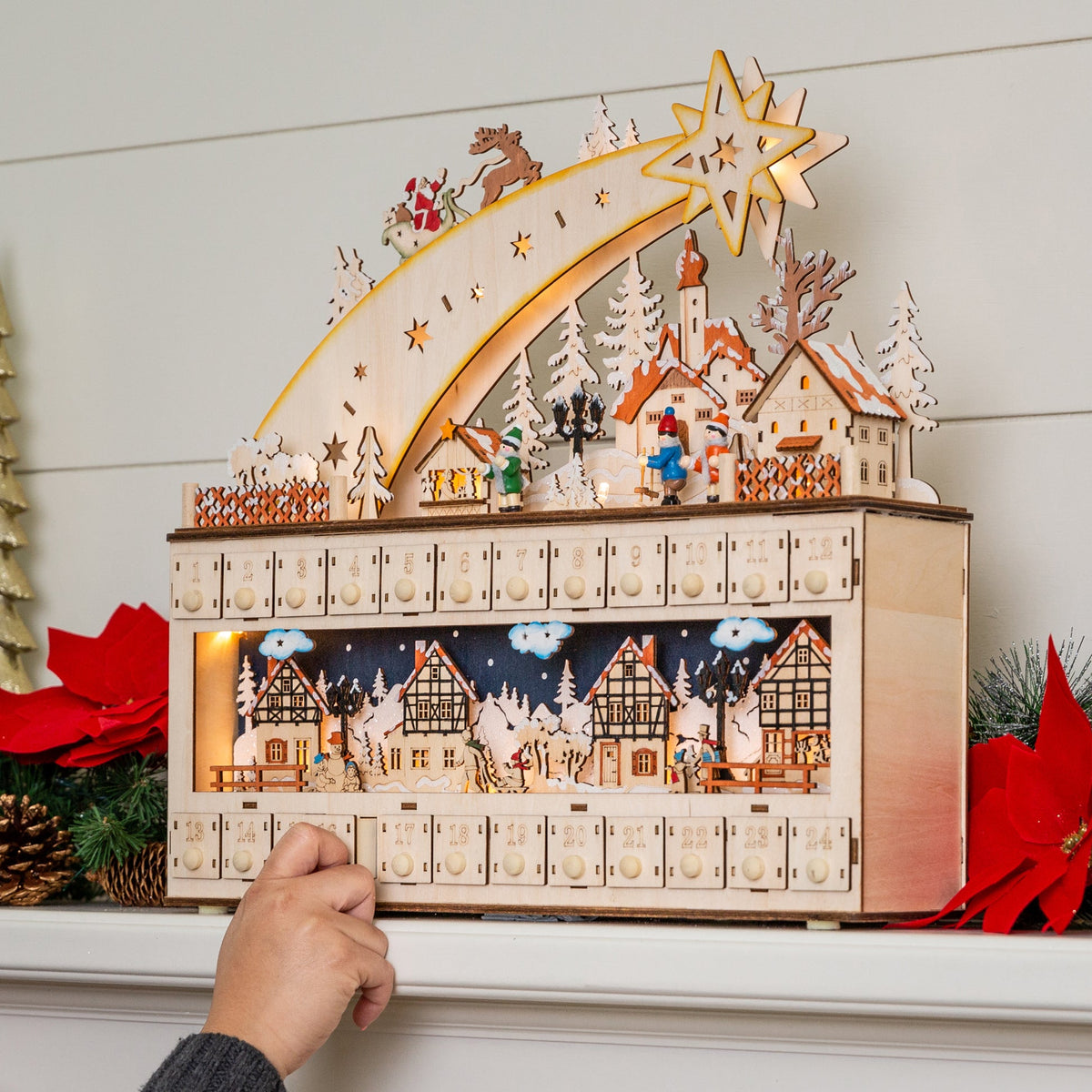Wooden shooting star Christmas advent calendar with warm LED light hanging on a festive wall display