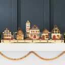 Pre-lit wooden Christmas village with warm LED lights arranged as festive mantel decor
